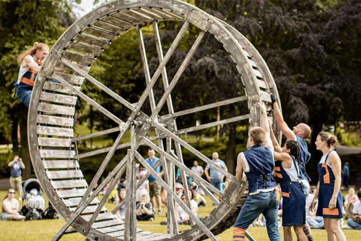 A giant wheel being controlled by performers